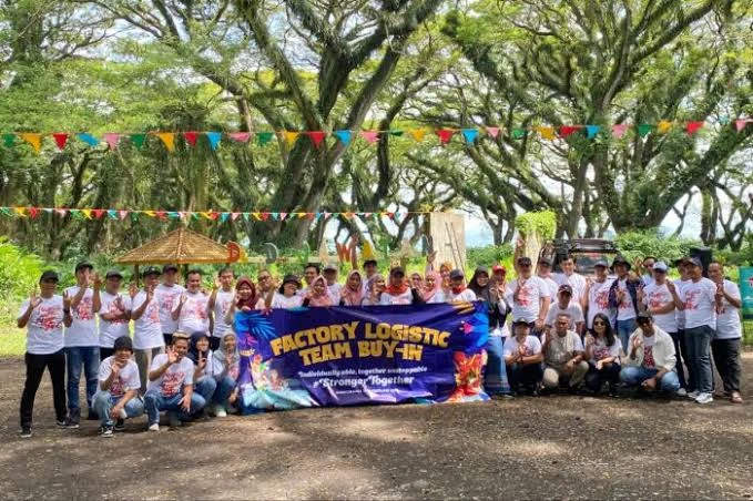 Rombongan korporat berfoto bersama di belakang banner acara mereka pada penutupan hari team building