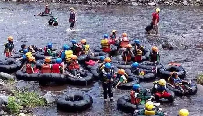 Peserta berhelm dan berpelampung menyusuri sungai dengan ban tunggal dalam sesi river tubing